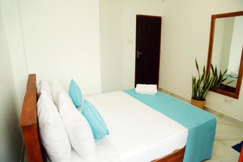 a bedroom with a bed with white sheets and blue pillows at Cocos in Midigama