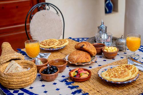 ein Tisch mit Brot und Körben mit Lebensmitteln und Orangensaft in der Unterkunft Riad Chams Marrakech in Marrakesch