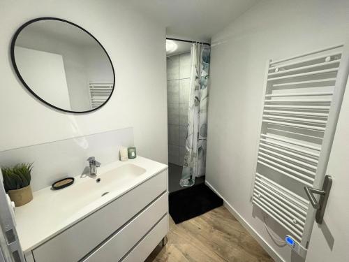 a white bathroom with a sink and a mirror at la pause landaise in Saint-Vincent-de-Paul