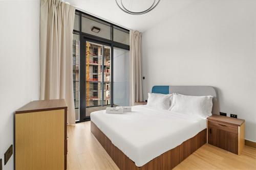 a bedroom with a large white bed and a window at FIRST CLASS 1BR Waterfront Bliss in Abu Dhabi