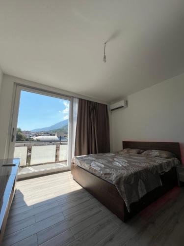 ein Schlafzimmer mit einem Bett und einem großen Fenster in der Unterkunft Mountain View Apartment in the heart of city in Peja
