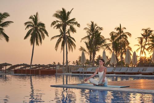 a woman sitting on a paddle board in the water at a resort at The Club by Fanar in Salalah
