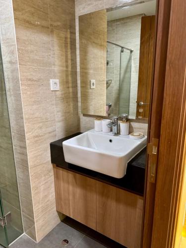ein Badezimmer mit einem weißen Waschbecken und einem Spiegel in der Unterkunft Luxury Apt in South Jakarta in Jakarta