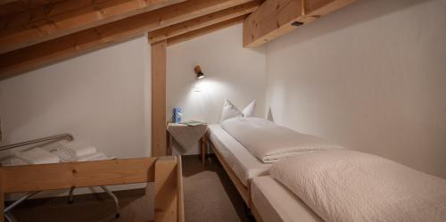 a bedroom with two beds and a wooden table at Hotel Acla Filli in Zernez