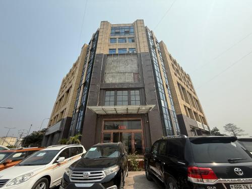 Un edificio alto con coches aparcados delante. en Easy home, en Brazzaville