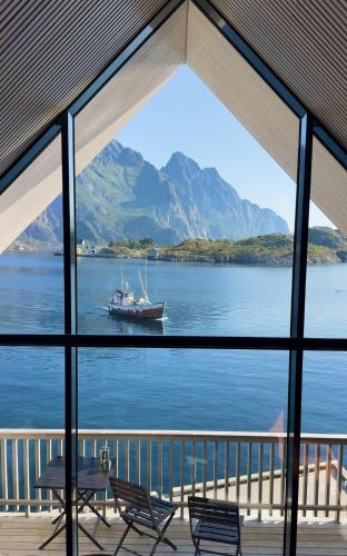 a view of a boat in the water from a window at CornerView Apartment Henningsvær in Henningsvær