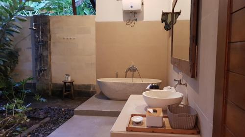 a bathroom with a bath tub and a sink at Melaya Cabanas in Candikesuma