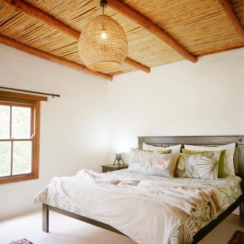 a bedroom with a large bed with a wooden ceiling at Watsonia Cottage at Waboom Family Farm in Stanford