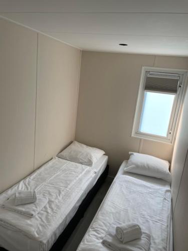 Dos camas en una habitación pequeña con ventana. en Bosperceeltje Putten, en Putten