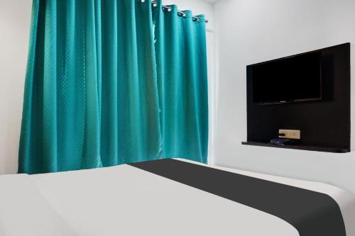 a bedroom with a green curtain and a bed and a tv at Super Aarambh Exotica in Pune