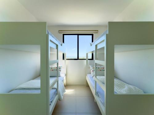two bunk beds in a room with a window at Apto 2 Quartos PISCINA Churrasqueira Wi-Fi Ar Condicionado Cozinha Complata Vaga de Garagem 400m PRAIA Ideal para Famílias ou Amigos Reserve Agora in Piçarras
