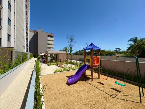 a playground with a purple slide and an umbrella at Apto 2 Quartos PISCINA Churrasqueira Wi-Fi Ar Condicionado Cozinha Complata Vaga de Garagem 400m PRAIA Ideal para Famílias ou Amigos Reserve Agora in Piçarras