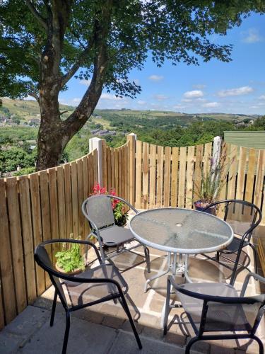 a patio with a table and chairs and a fence at The Scullery - a quirky annex with wood fire in Huddersfield