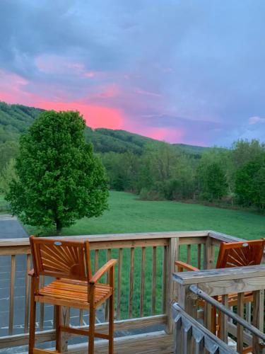 two chairs on a deck with a view of a field at Riverbend Berkshire East Basecamp in Charlemont