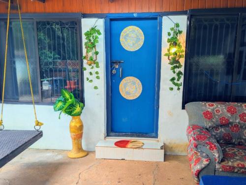 a blue door with a plant next to a couch at Coral Reef Malpe - Udupi in Udiyāvara