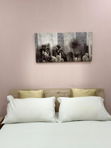 a bed with two pillows and a painting on the wall at Casa Vacanza da Rosy in Boscotrecase