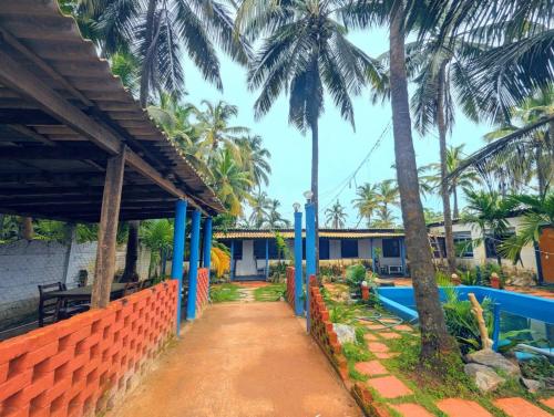 a pathway leading to a house with palm trees at Coral Reef Malpe - Udupi in Udiyāvara