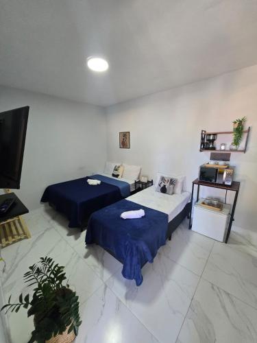a room with two beds and a tv in it at Loft Recanto Dos Pinheiros in Rio das Ostras