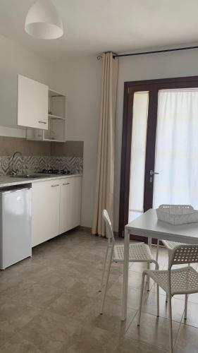 a kitchen with a table and a table and chairs at CASA VACANZE gli ULIVI 23 in Sìnnai