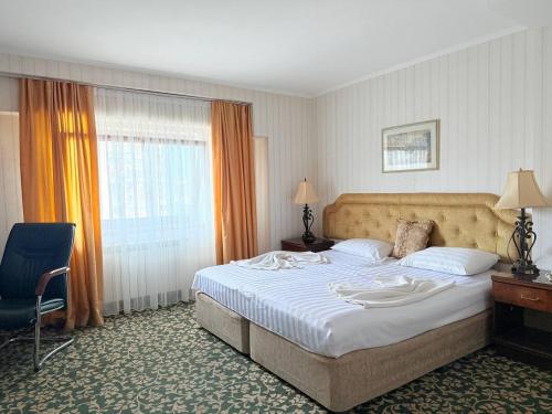 Una habitación de hotel con una cama grande y una silla. en Shirak Hotel, en Ereván