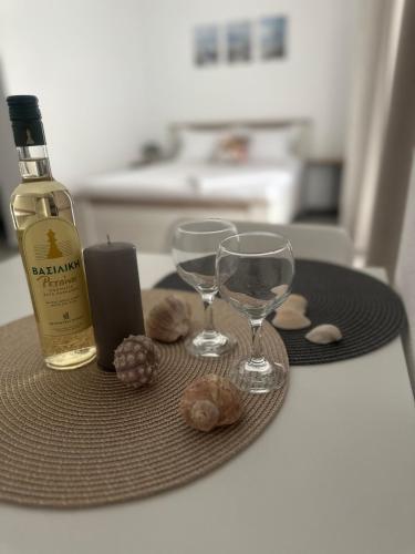 a bottle of wine and two glasses on a table at Самостоятелно студио с градина 3 in Asprovalta