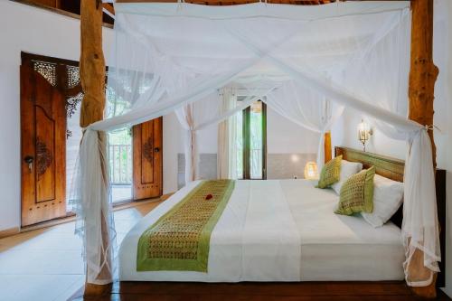 a bedroom with a white bed with a canopy at Yeh Pulu House in Ubud