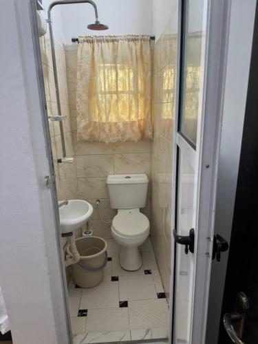 a small bathroom with a toilet and a sink at Home feel in Ikeja