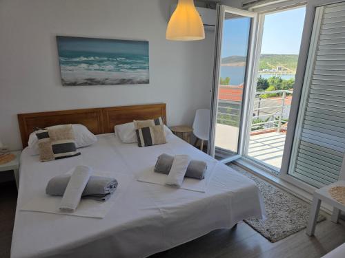 a bedroom with a white bed with pillows and a balcony at Bed & Breakfast Dora in Rovanjska