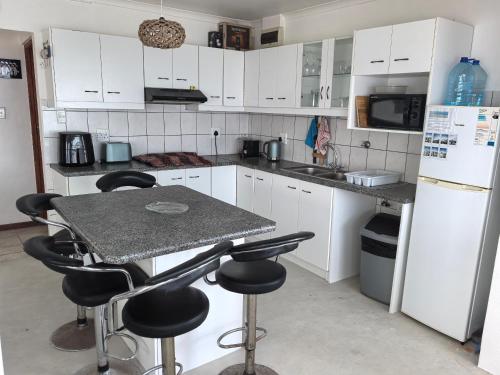 a kitchen with white cabinets and a table with stools at Seaside Escape in Pearly Beach