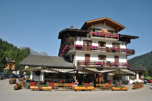 a large building with tables and chairs in front of it at Hotel Stella Alpina in Falcade
