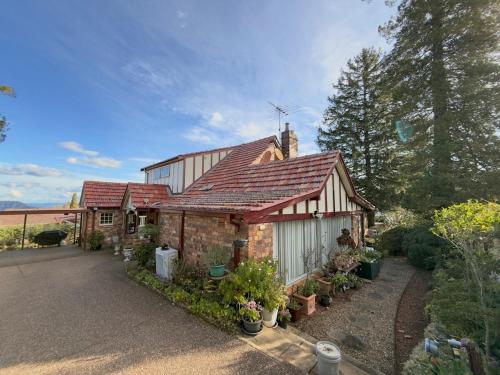 a brick house with a red roof and some plants at Echo point Cottage in Katoomba