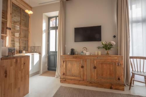 a kitchen with a wooden cabinet with a television on the wall at Les Écuries de Juranville in Bourges
