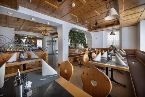 a restaurant with wooden ceilings and tables and chairs at Hotel Acla Filli in Zernez