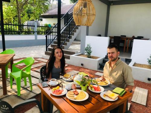 a man and woman sitting at a table with food at Silver Palm Resort Anuradhapura in Anuradhapura
