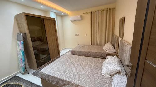 a small bedroom with two beds and a mirror at جاردن هوم الارضي مع البول Garden Home with pool ال عصام in 6th Of October