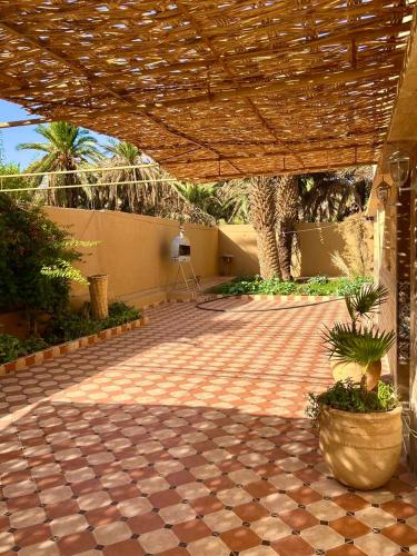 a patio with a brick floor and a wooden umbrella at Traditional,spacious Villa, Arfoud in Erfoud