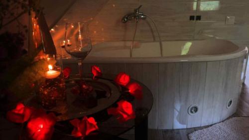 a bathroom with a tub with a table and wine glasses at FLÓRA VENDÉGHÁZ A BALATONNÁL in Lovas