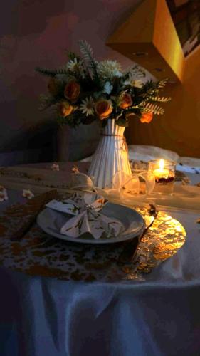 a table with a plate and a vase with flowers at FLÓRA VENDÉGHÁZ A BALATONNÁL in Lovas