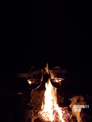 two wine glasses sitting next to a fire at FLÓRA VENDÉGHÁZ A BALATONNÁL in Lovas
