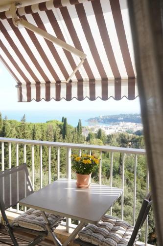 a table and chairs on a balcony with a striped umbrella at Casa Mare - Sea View, Home Cinema, Parking in Menton