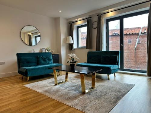 a living room with two green chairs and a coffee table at 2 Bed Duplex with En-suite 5 mins walk from city centre in Leeds