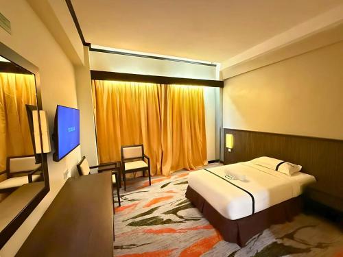 a hotel room with a bed and a television at Seeds Hotel Premier Sri Petaling in Kuala Lumpur