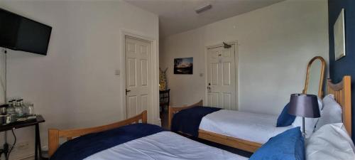 a bedroom with two beds and a flat screen tv at The Weir Hotel in Walton-on-Thames
