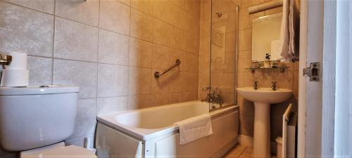 a bathroom with a tub and a sink and a toilet at The Weir Hotel in Walton-on-Thames