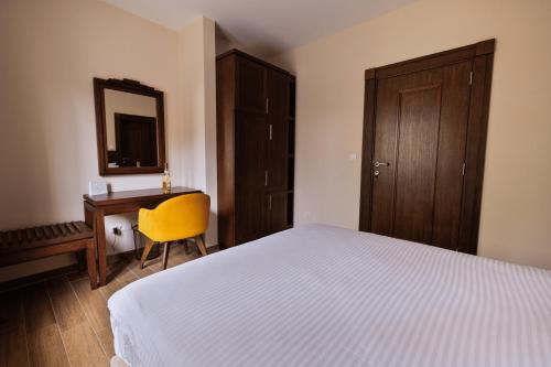a bedroom with a bed and a desk with a yellow chair at Vikendica Aleksandrović Ježevac in Topola