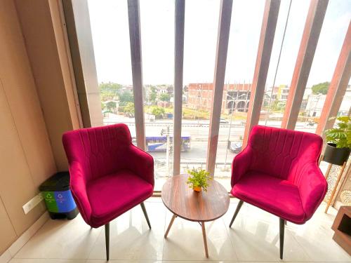 two red chairs and a table in front of a window at Hotel La Casa, Amritsar #swimming pool #prime location #luxury rooms #best selling near golden temple in Amritsar