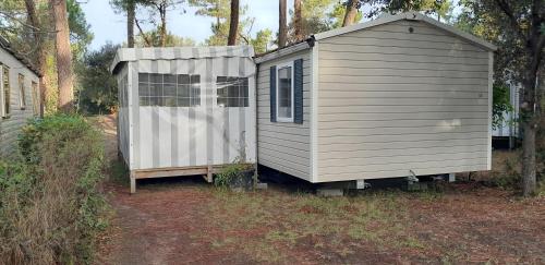 a small shed sitting next to a house at MOBIL HOME CONFORT PLUS - 40m2 - 3ch - 2 SDB - Camping 4 étoiles - BONNE ANSE 56 in Les Mathes