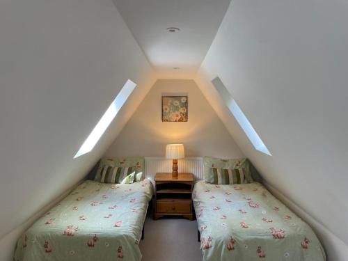 a attic bedroom with two beds and a lamp at Luxury Woodland Stay in Cheltenham in Cheltenham