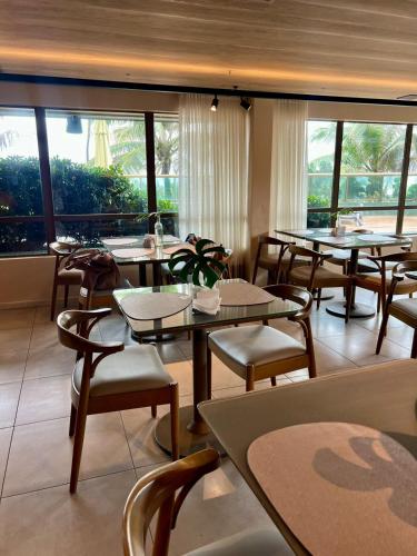 a restaurant with tables and chairs and large windows at Refúgio do Mar 705 - Condomínio Edifício Ritz Suítes Home Service in Maceió