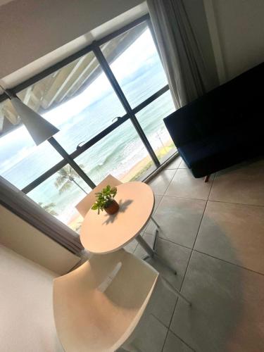 a table with a plant on it in front of a window at Refúgio do Mar 705 - Condomínio Edifício Ritz Suítes Home Service in Maceió